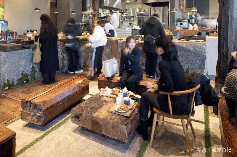 テーブルと椅子の組み合わせ。床にｆは古木の枕木、カウンターには施工担当者が伊豆半島の石切場で選んだ小松石が用いられている。